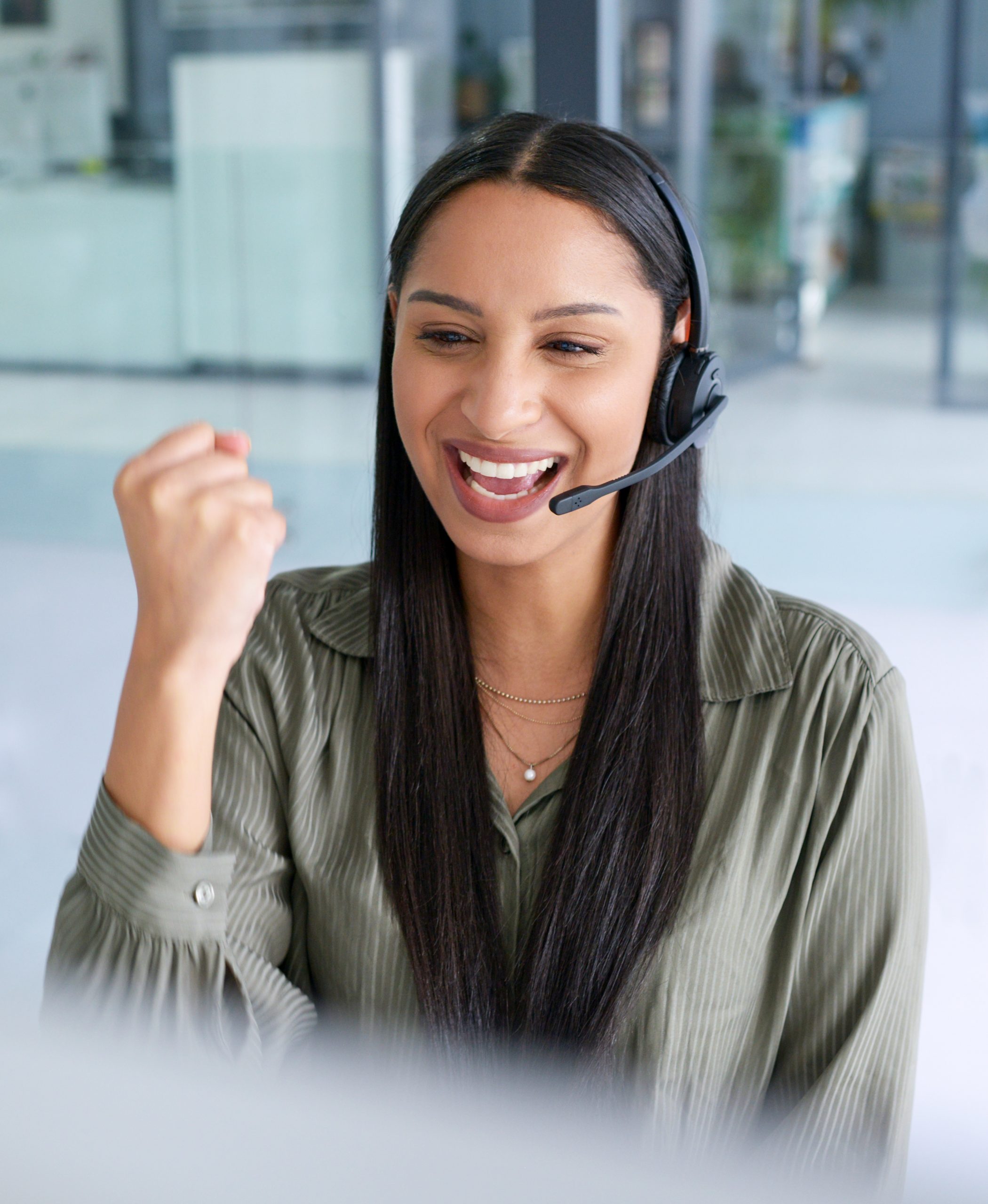 Shot of a young call centre agent cheering while working in an office.